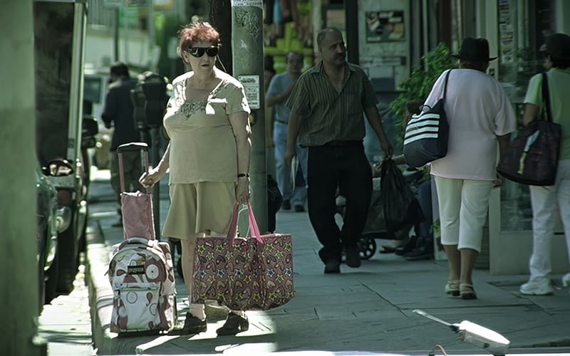 A woman walking down the street with her luggage.
