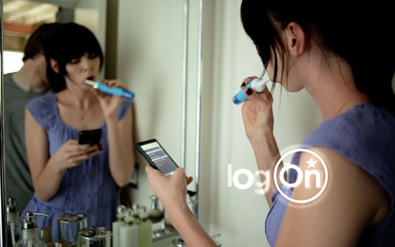 A woman brushing her teeth with an electric toothbrush.