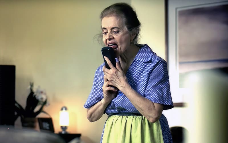 A woman is holding her phone up to her mouth.