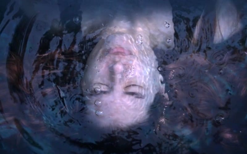 A woman is submerged in water with her head above the ground.
