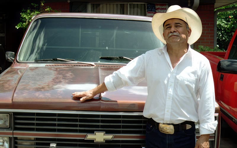 A man in white shirt and hat standing next to a truck.