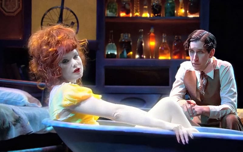 A doll in the bathtub with another doll.